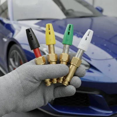 Close-up of a hand selecting different colored quick-connect nozzles for a pressure washer, with a blurred car in the background. 