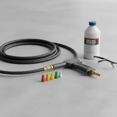Essential tools for fast oil stain removal with a pressure washer, including a pressure washer, degreaser, nozzles, and safety glasses.